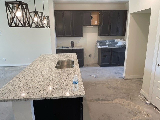 island kitchen with black cabinets and stone countertops
