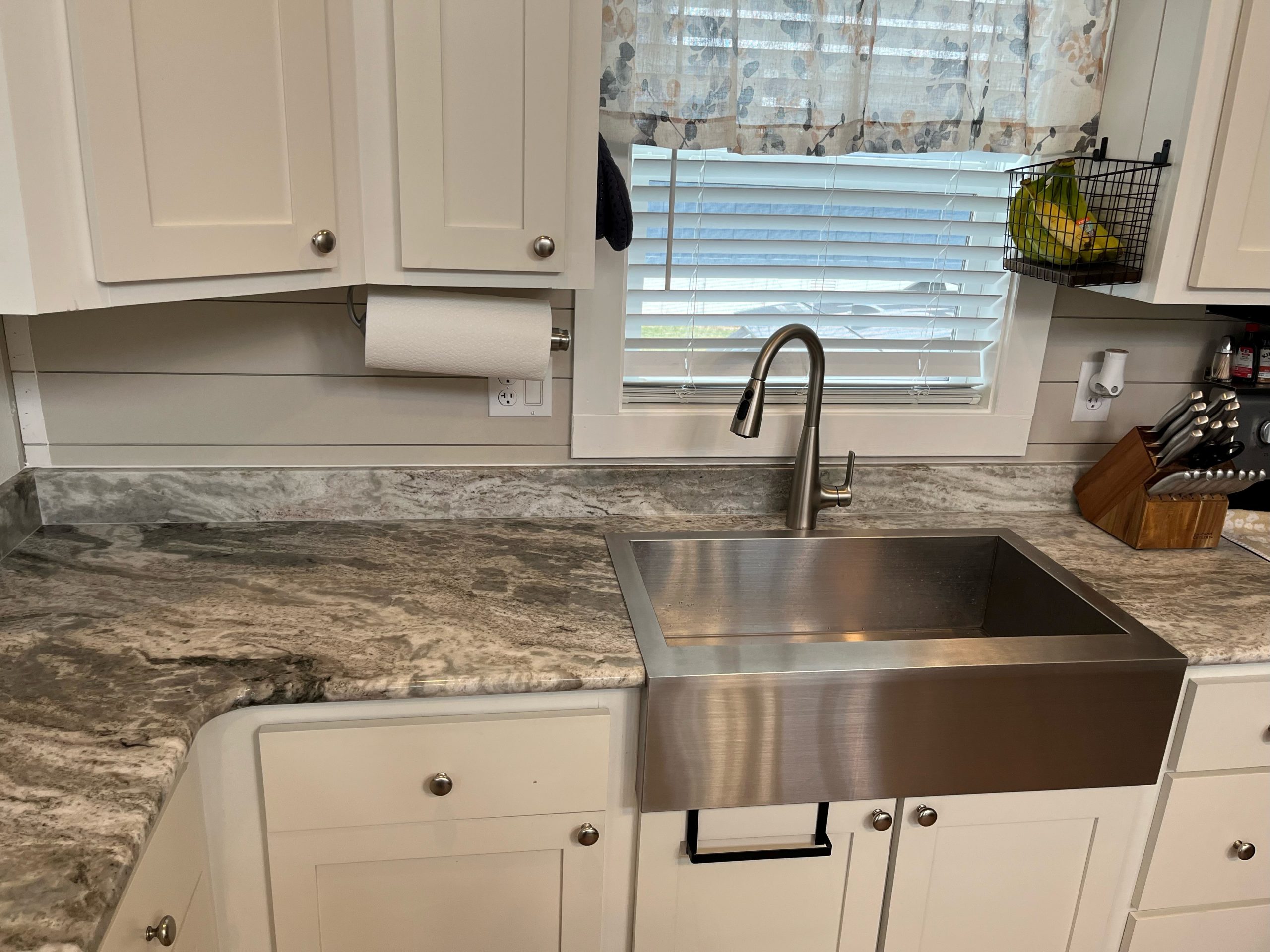 kitchen with stainless steel sink, white cabinets, and stone countertops