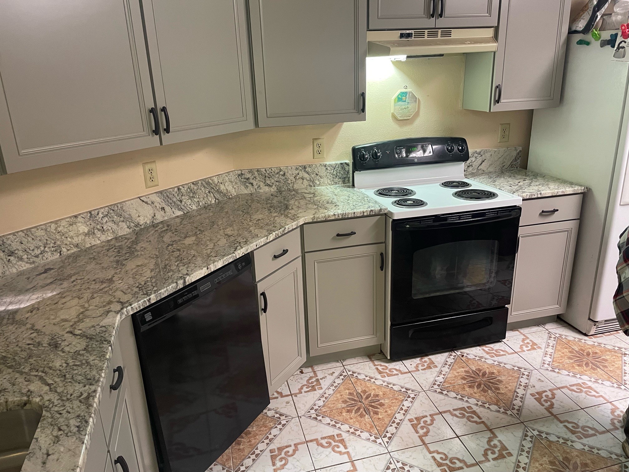 a modern kitchen with cool toned granite countertops and gray cabinets