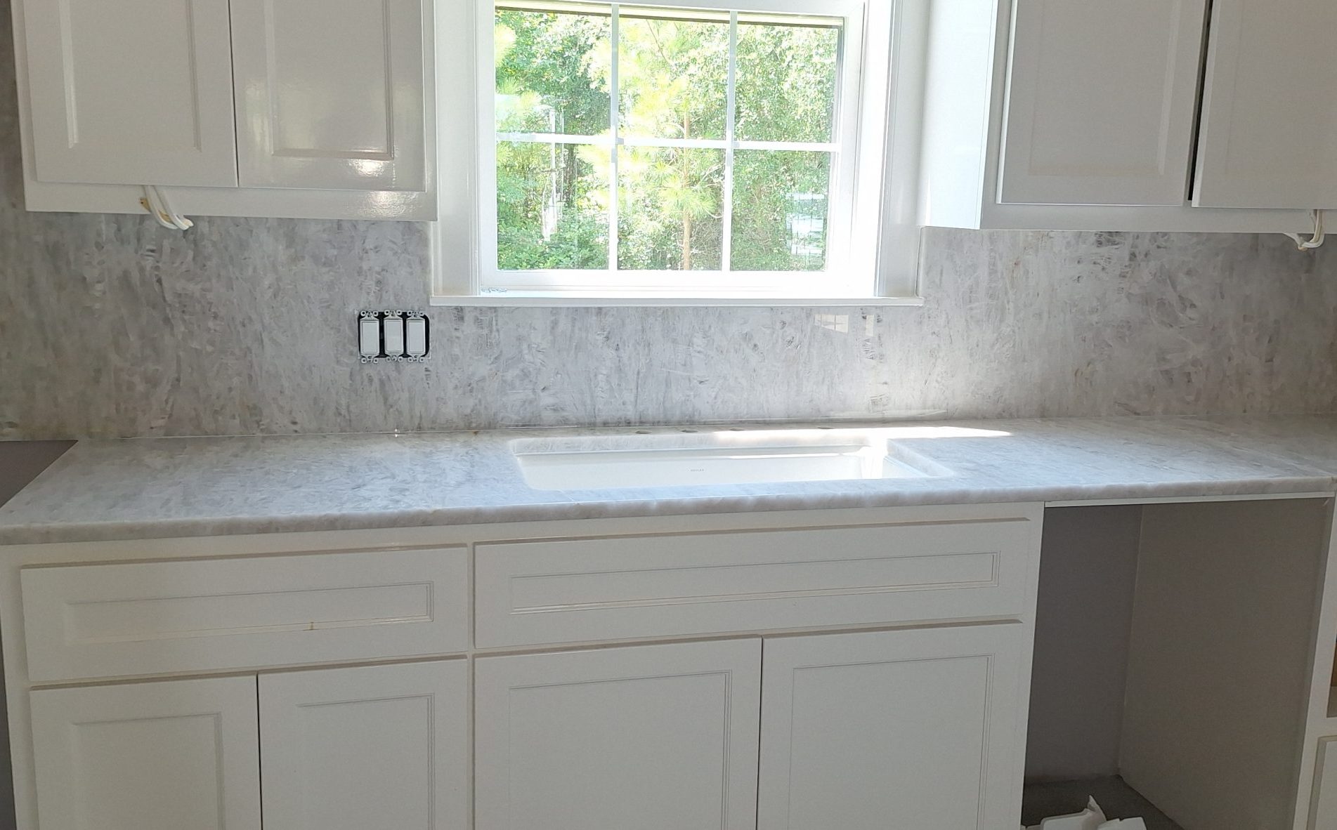 modern white kitchen with granite backsplash and matching countertops