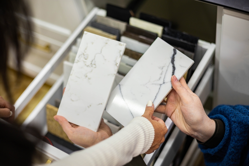 Why Hire a Countertop Designer for Your Remodel Project? Closeup hands creative female interior designer and customer choosing marble stone color for kitchen or facades. Top view woman client consulting to decorator choice home improvement materials.