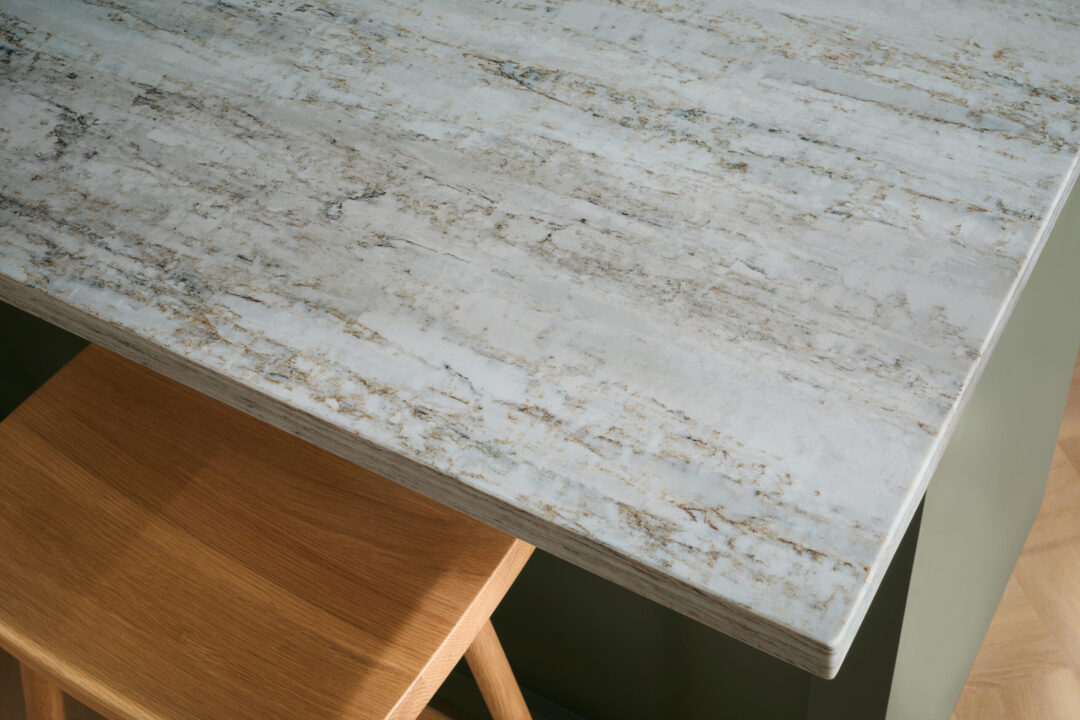 Close up of a quartz eased edge countertop island in a green kitchen.