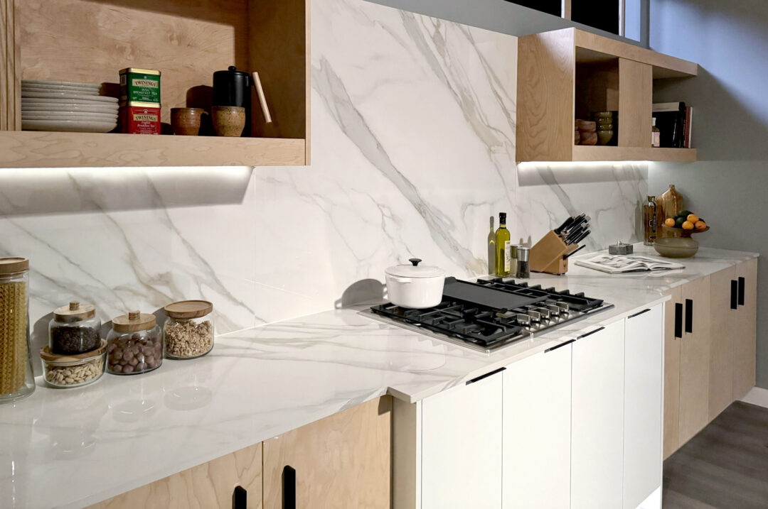 Neutral toned kitchen with white porcelain countertops and full height backsplash behind stove.